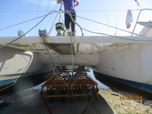 close up of the underneath of a catamaran beneath the 2 hulls with the trailer showing