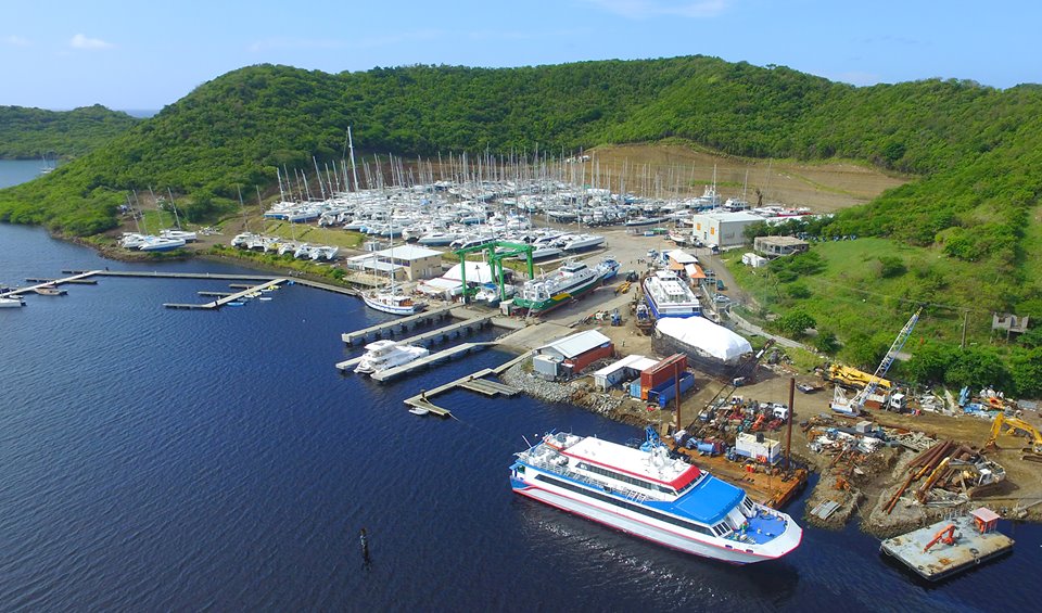 aerial view of a boatyard with many boats standing on the hard and marina pontoons with a large ferry in the foreground