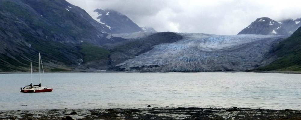 yacht migration at anchor in Alaska with a glacier behind and snow topped mountains