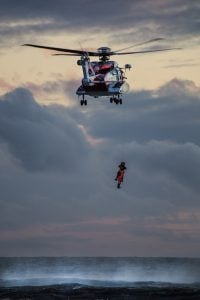 A helicopter winches a person from the sea