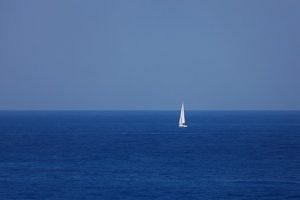 a lone yacht in the middle of the blue sea sailing