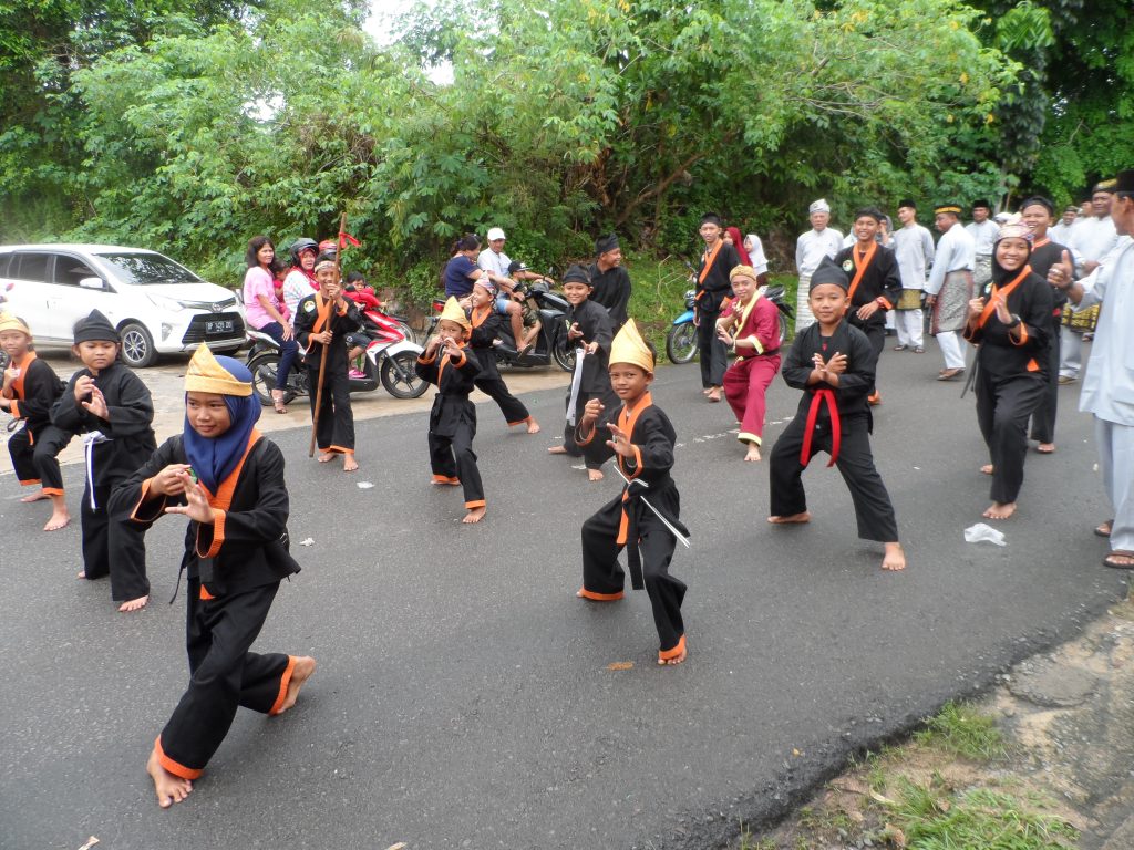 Locals dressed up in local dress taking part in a parade on the road doing poses as part of a dance