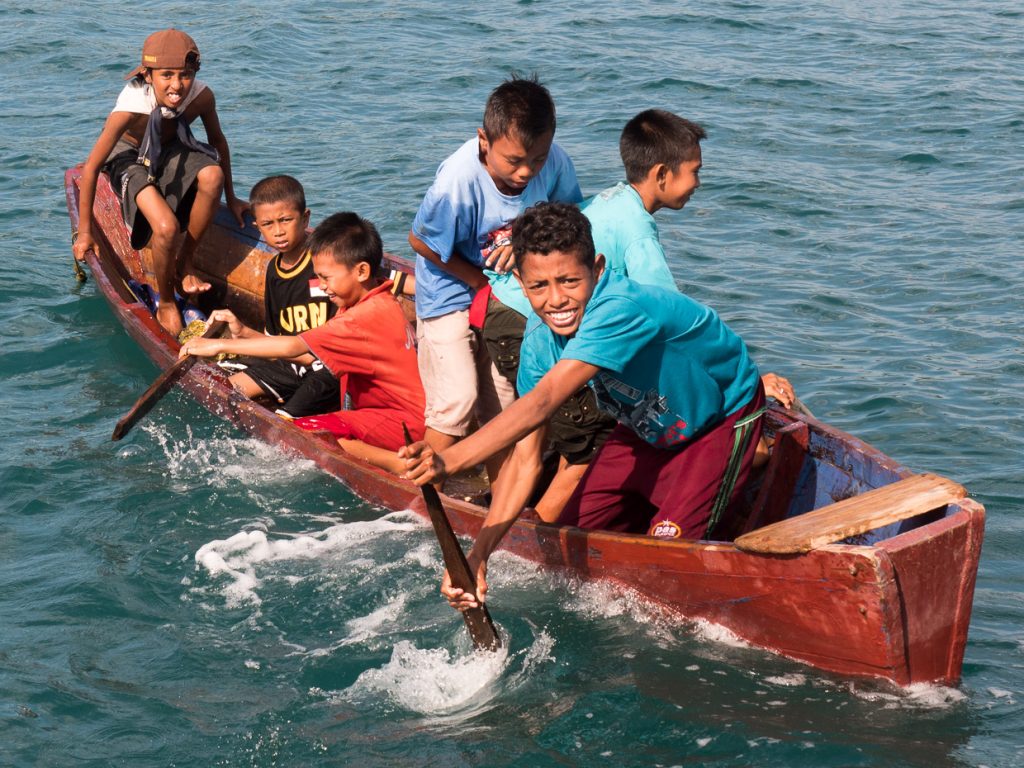 local boys in a very simple canoe smiling and playing