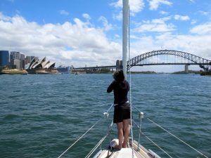 lisa standing on the bow of the boat heading for sydney bridge with the opera house to port