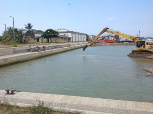 a marina basin, empty except for a digger excavating