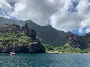 tall rugged ominous mountains covered in green fertile growth and black volcanic soil rising up from the sea