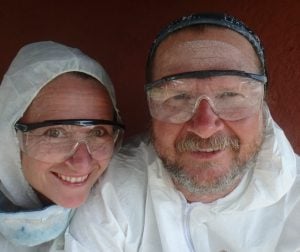 couple dressed in white overhauls and clear goggles, dressed to paint the keel of their boat