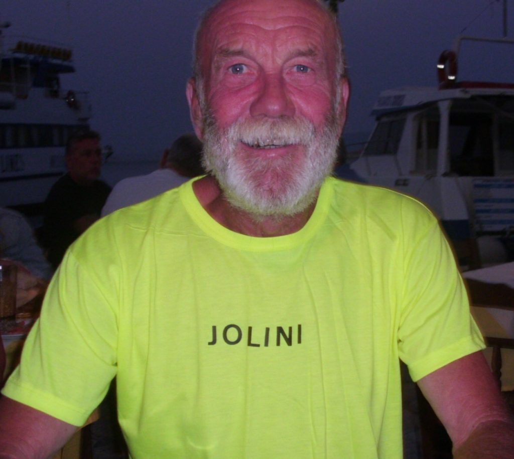 jerry with a red fac and white beard wearing a bright yellow t shirt with his boat name on it