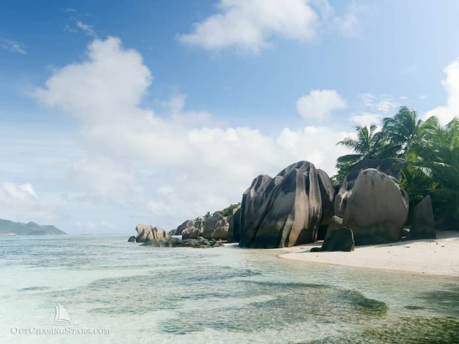 shallow reef up to a white beach with great big boulders on the shore