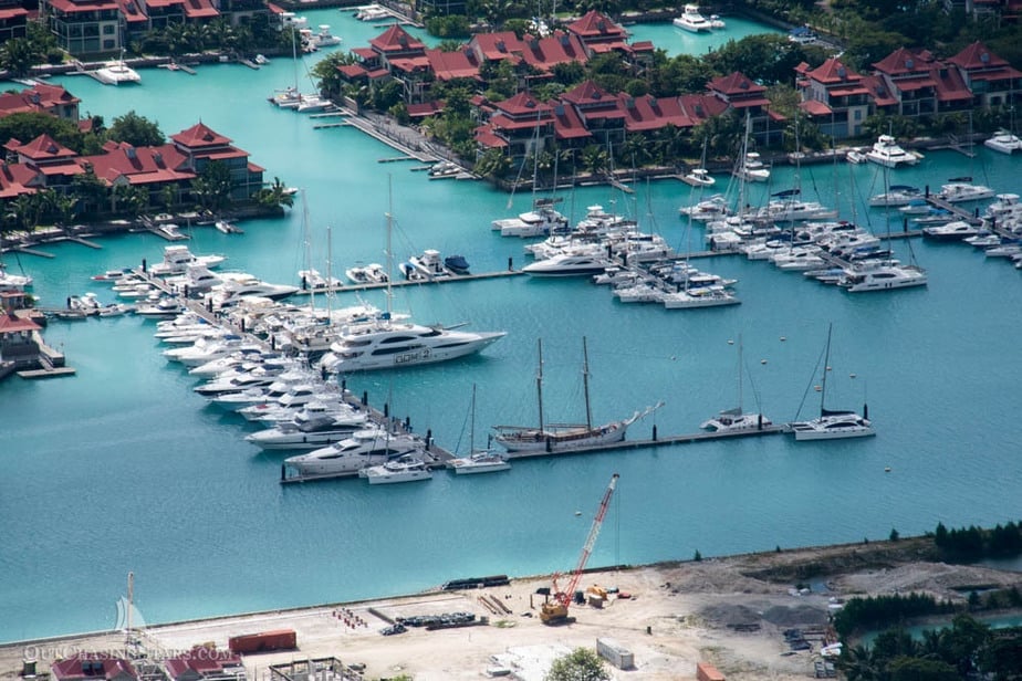 aerial view of a marina in a lagoon with apartments/hotels behind and a white beach in the foreground