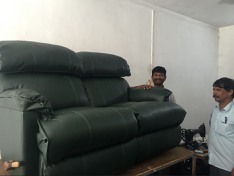 A green sofa re upholstered with the 2 men who did the job standing next to it