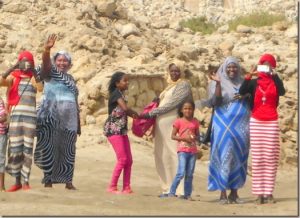 a line of ladies and children dressed with their heads and bodies covered waving and smiling and very colorful