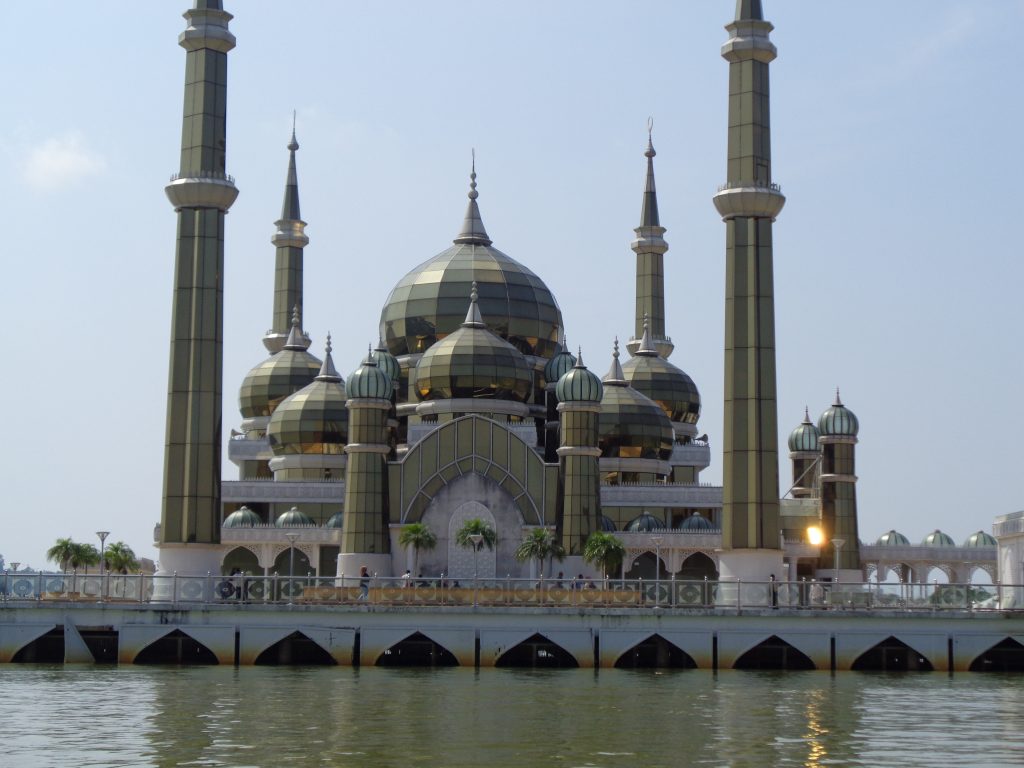 a gold and white palace on the waters edge with minurettes and pointed domes