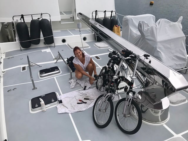 Jay the lady crouched down on deck next to bicycles doing some repair work