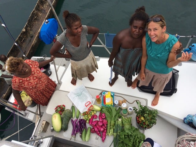 looking down at the deck of the boat where Gemma is standing with three local ladies and on the deck are spread a variety of vegetables and fruit