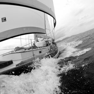 black and white photo from the bow of the boat looking down the leeward side with the wake of the boat and sails out full
