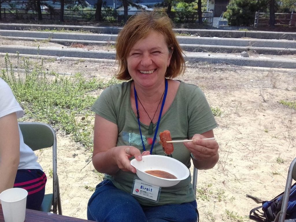 Woman sitting down holding a plate of food.