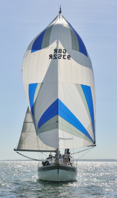 Head on view of yacht sailing with spinnaker flying.