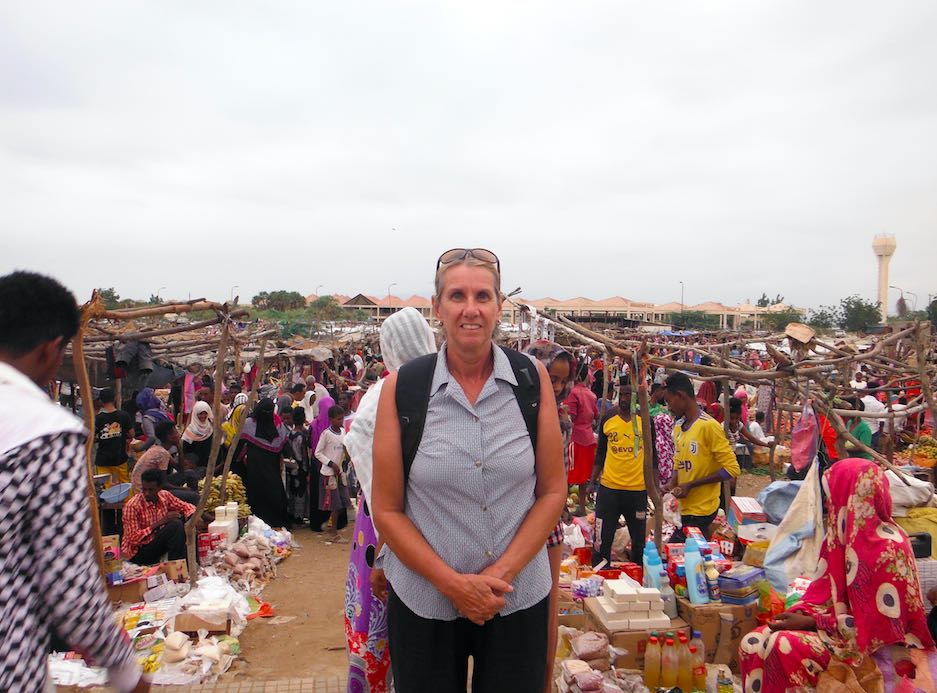 Woman standing among a crowd of people at a marketplace.