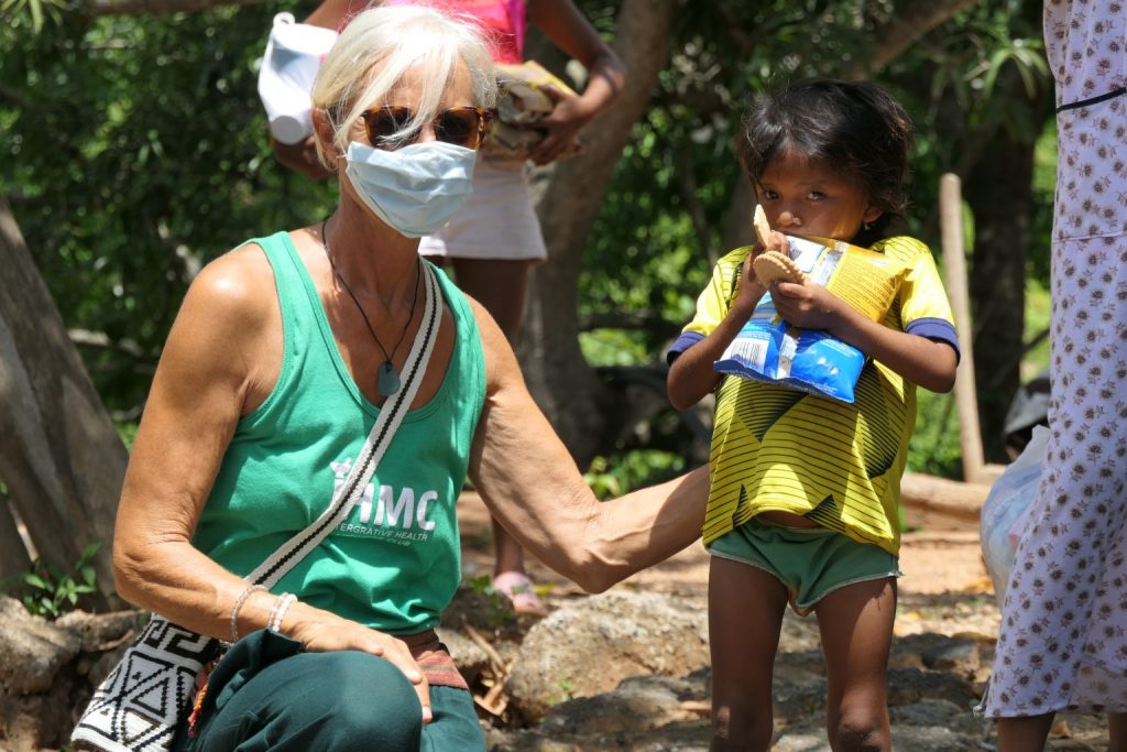 a lady wearing a face mask next to a small child holding a food bag