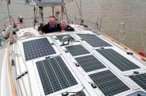 Man and woman in cockpit of yacht looking out over solar panels